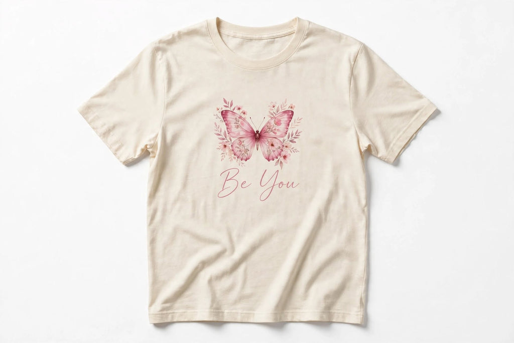 Cream women's graphic tee with a pink butterfly, floral details and Be You lettering